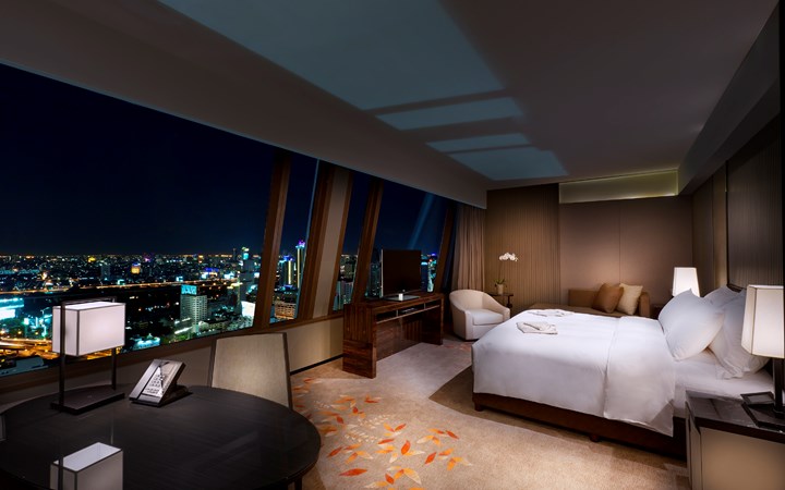 The Okura Prestige, room with a glass wall and view of Bangkok skyline at night
