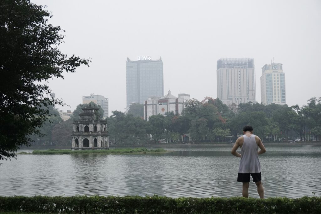 Side View Of View Of Turtle Tower In The Middle Of Hoan Kiem Lake And The City Behind