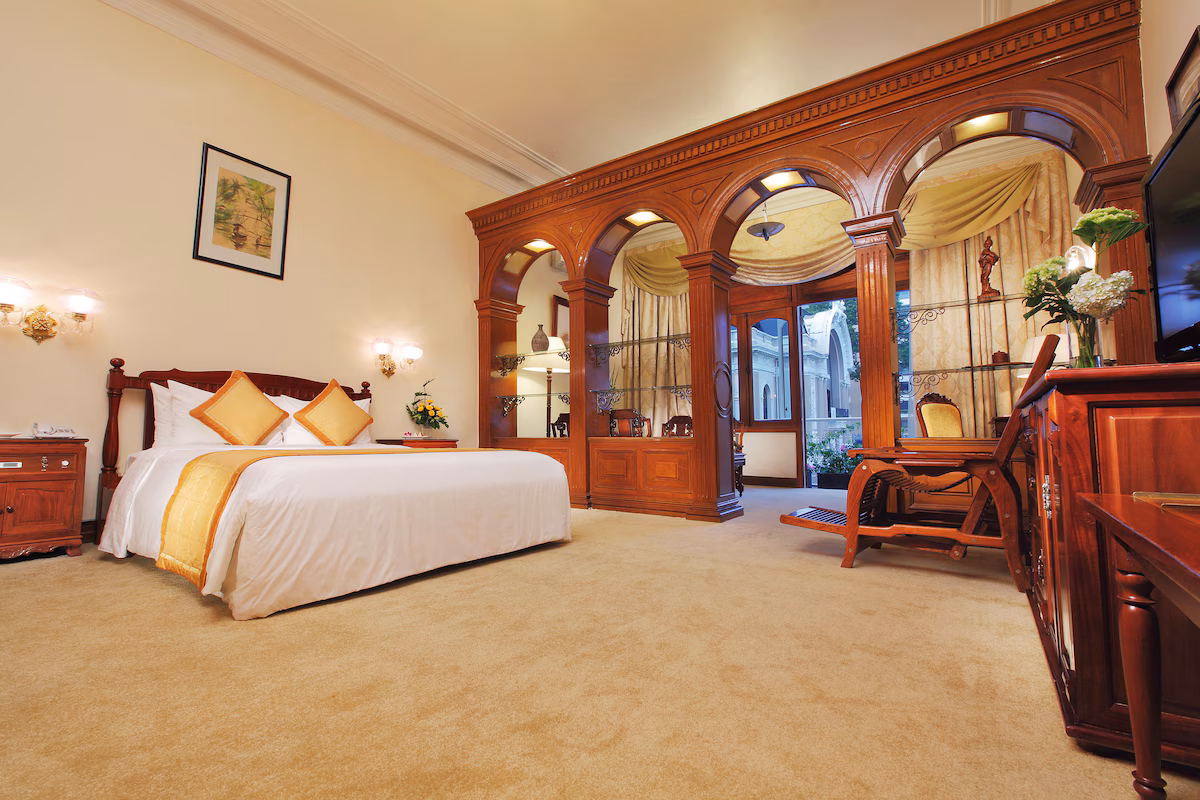 Hotel Continental Saigon, room with dark wood furnishings and decorative arches