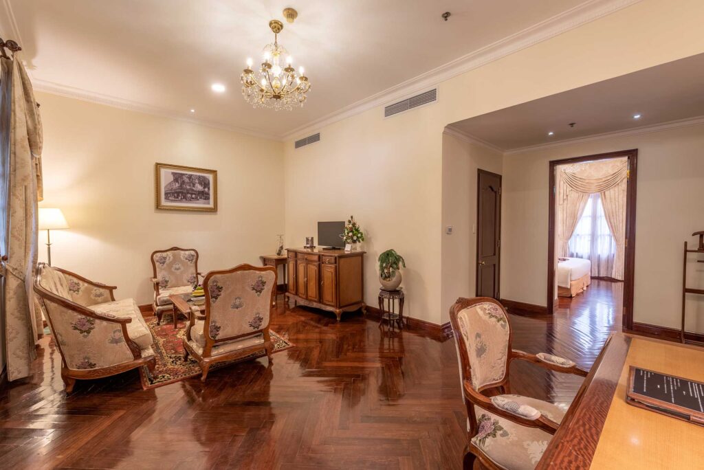 Hotel Grand Saigon, room with a large living room, work desk, And Dark wood Flooring
